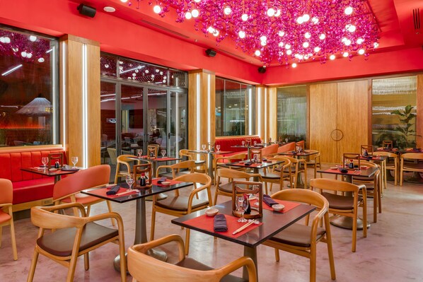 A restaurant interior with red walls, wooden furniture, and a ceiling adorned with hanging lights.