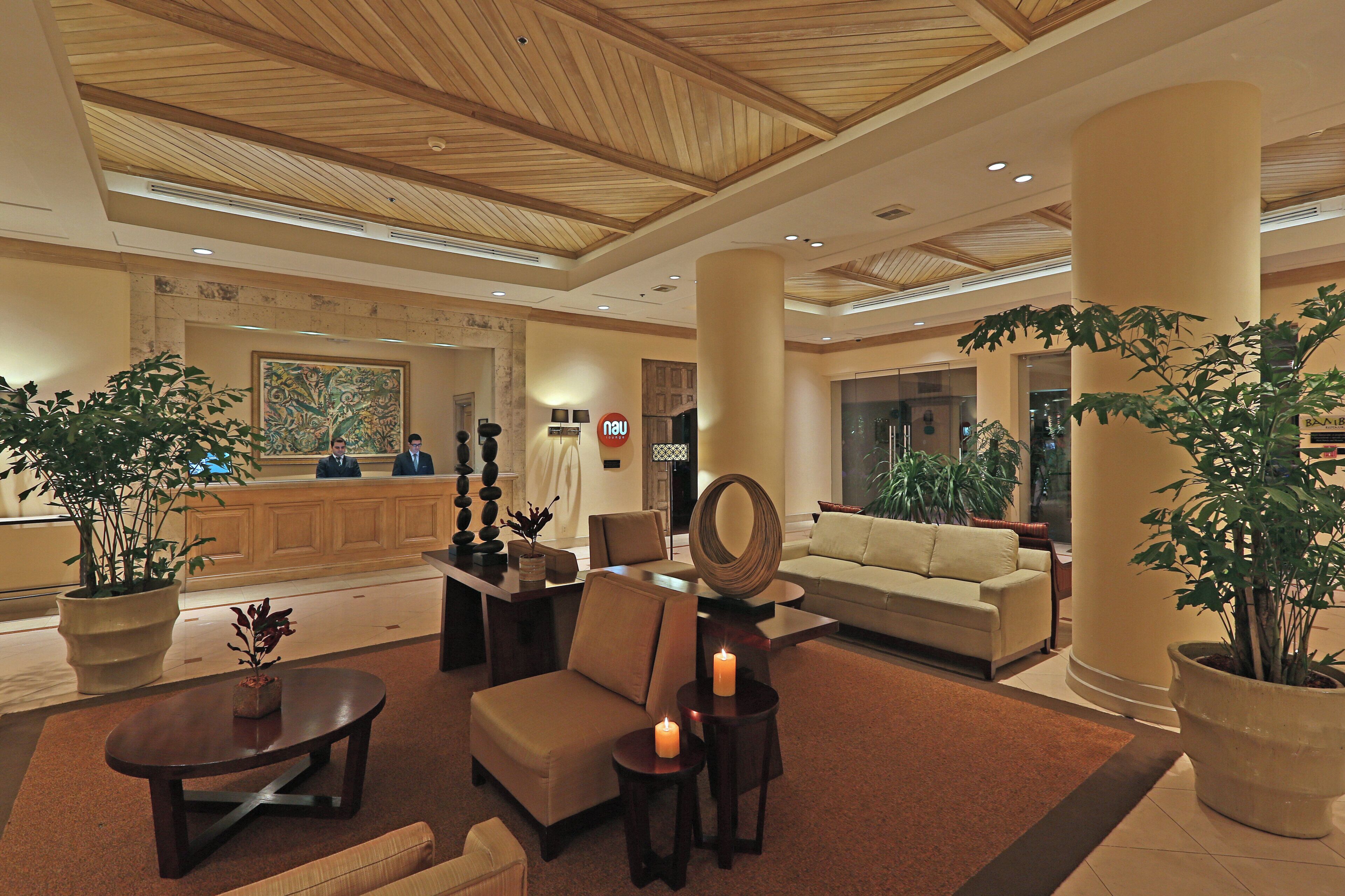 A lobby with a reception desk, seating area, and a large mirror.