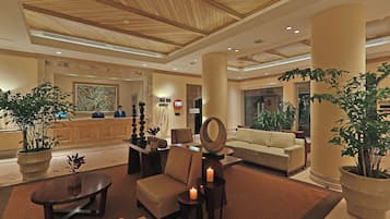 A lobby with a reception desk, seating area, and a large mirror.