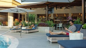 Un espace aménagé au bord de la piscine, avec des chaises longues, des parasols et une piscine.