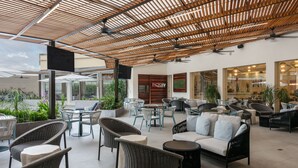 An outdoor seating area with wicker furniture, a cafe, and a view of the city. - InterContinental Real San Pedro Sula by IHG (San Pedro Sula)