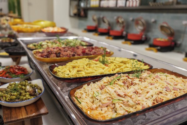 A buffet with various dishes including pasta, salads, and other prepared foods.