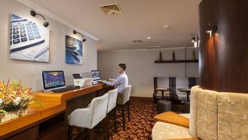 A hotel lobby with a reception desk, bar area, seating, and artwork on the walls.