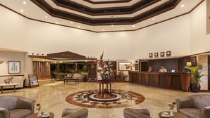 A hotel lobby with a reception desk, seating area, and a decorative centerpiece. - Prime Plaza Hotel - Purwakarta (Cikampek)