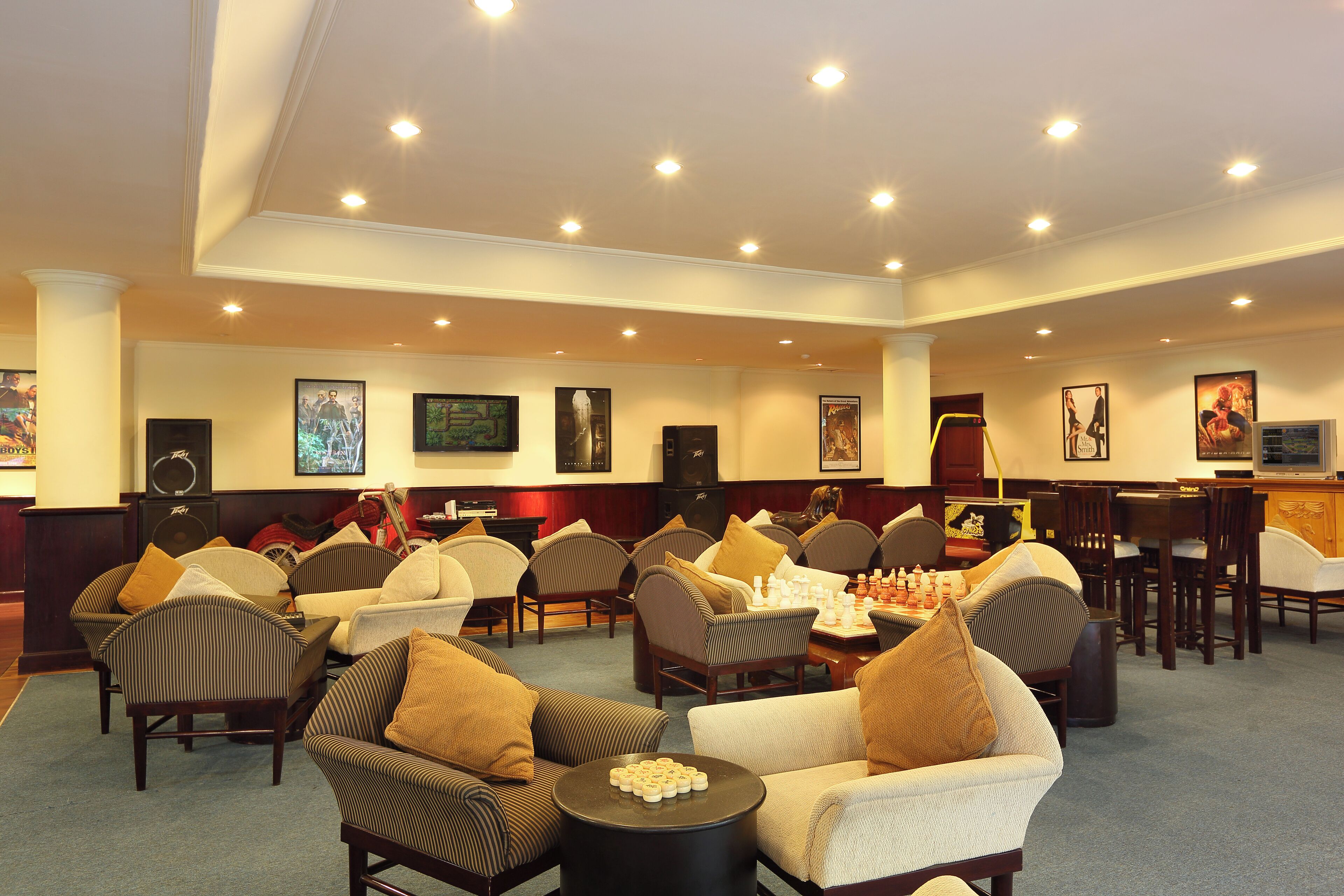 A spacious lounge area with multiple seating options, including sofas and armchairs, arranged around a central table with a chess set.
