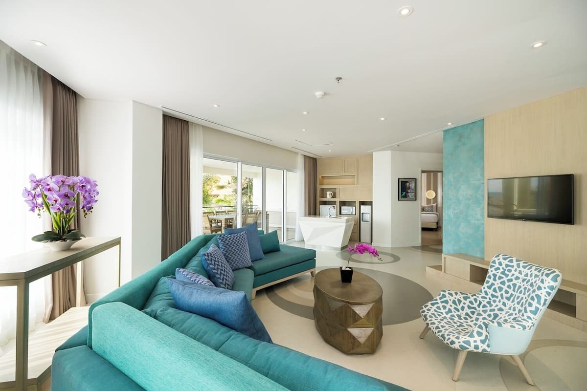 Un salon moderne avec un canapé de couleur turquoise, une table basse et un fauteuil à motifs.