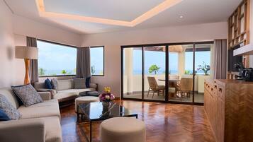 Un salon moderne avec un canapé, une table basse et une vue sur l’océan grâce à de grandes fenêtres.