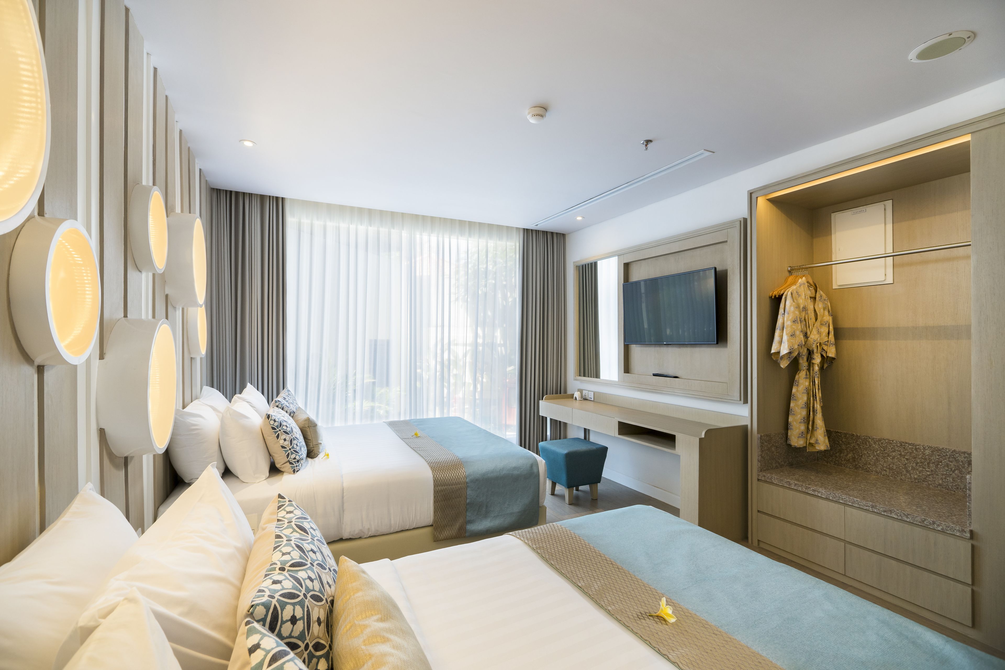 Une chambre d’hôtel avec deux lits, un bureau, une télévision et une armoire.