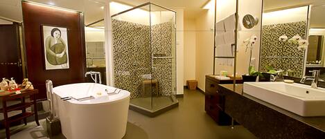A modern bathroom with a large bathtub, a separate shower area, and a vanity with a mirror.