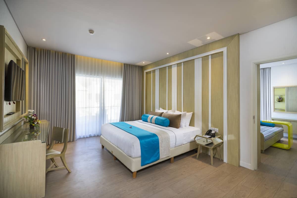 Une chambre d’hôtel moderne dotée d’un grand lit, de tables de chevet, d’un bureau et d’un coin salon.