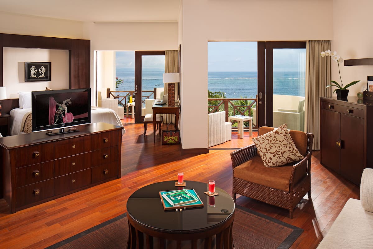 Une chambre d’hôtel avec un balcon, une télévision, un coin repas et un canapé.