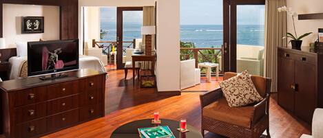 A hotel room with a balcony, a TV, a dining area, and a sofa.