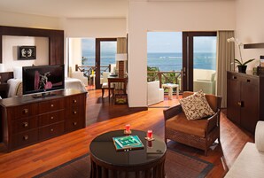 Ein Hotelzimmer mit Balkon, Fernseher, Essbereich und einer Couch.