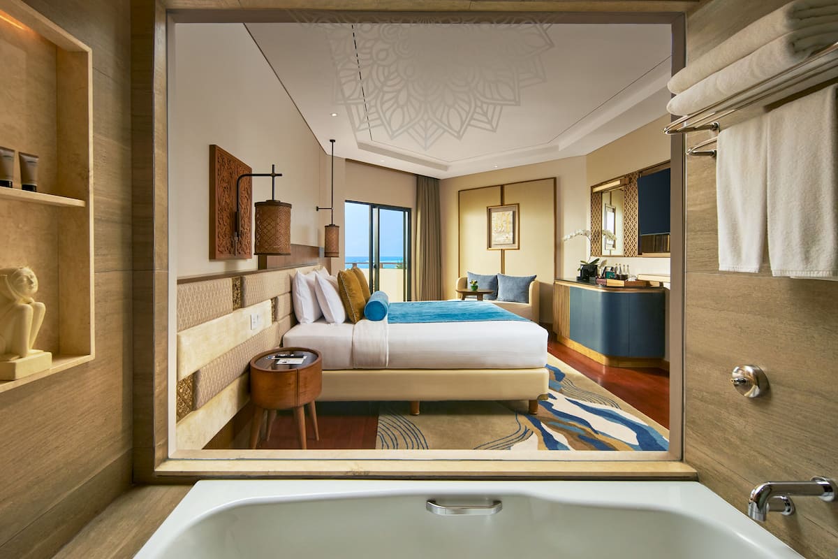 Une chambre d’hôtel moderne avec un grand lit, un bureau et une salle de bain équipée d’une baignoire.