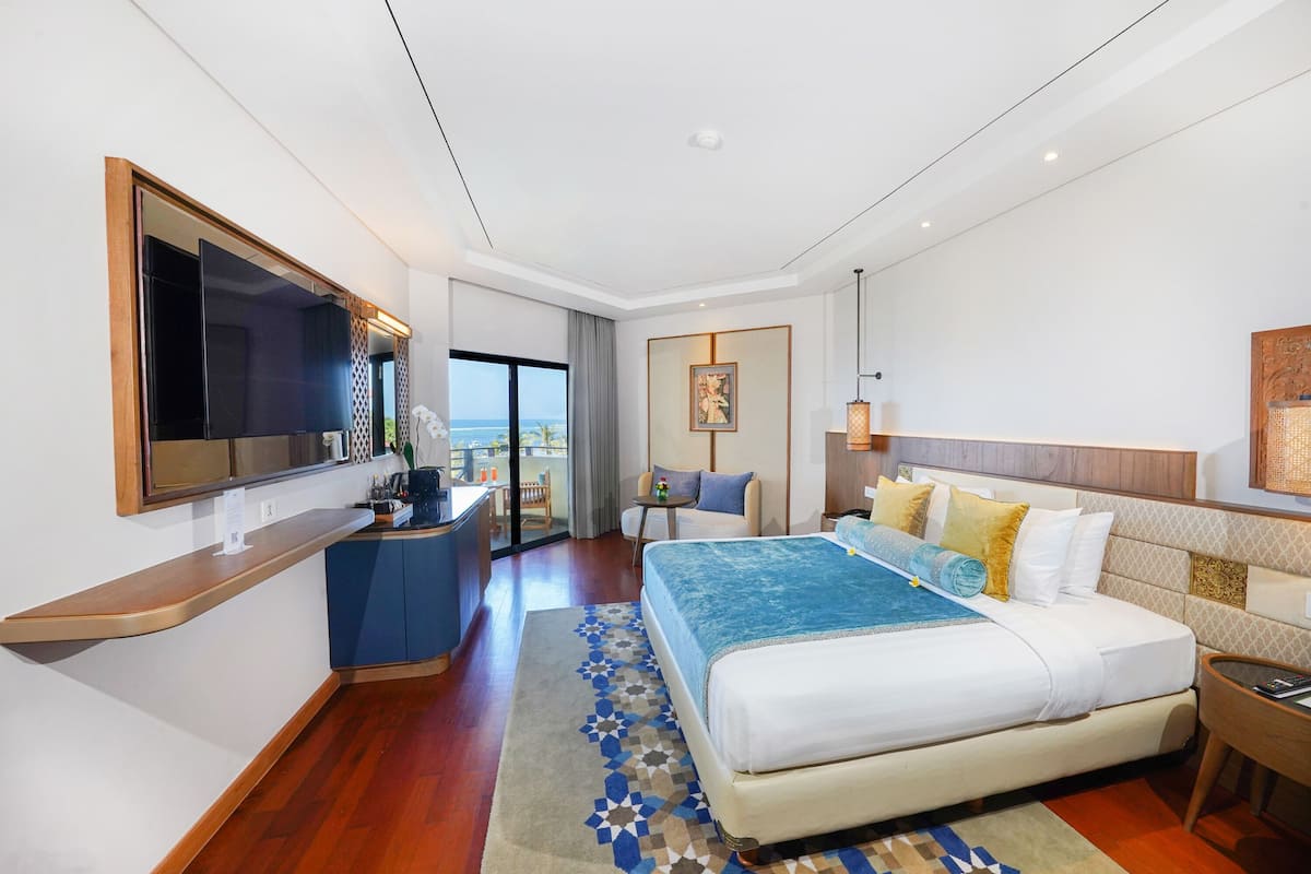 Une chambre d’hôtel moderne dotée d’un grand lit, d’un bureau avec un téléviseur à écran plat, d’une petite table et d’un balcon avec vue.