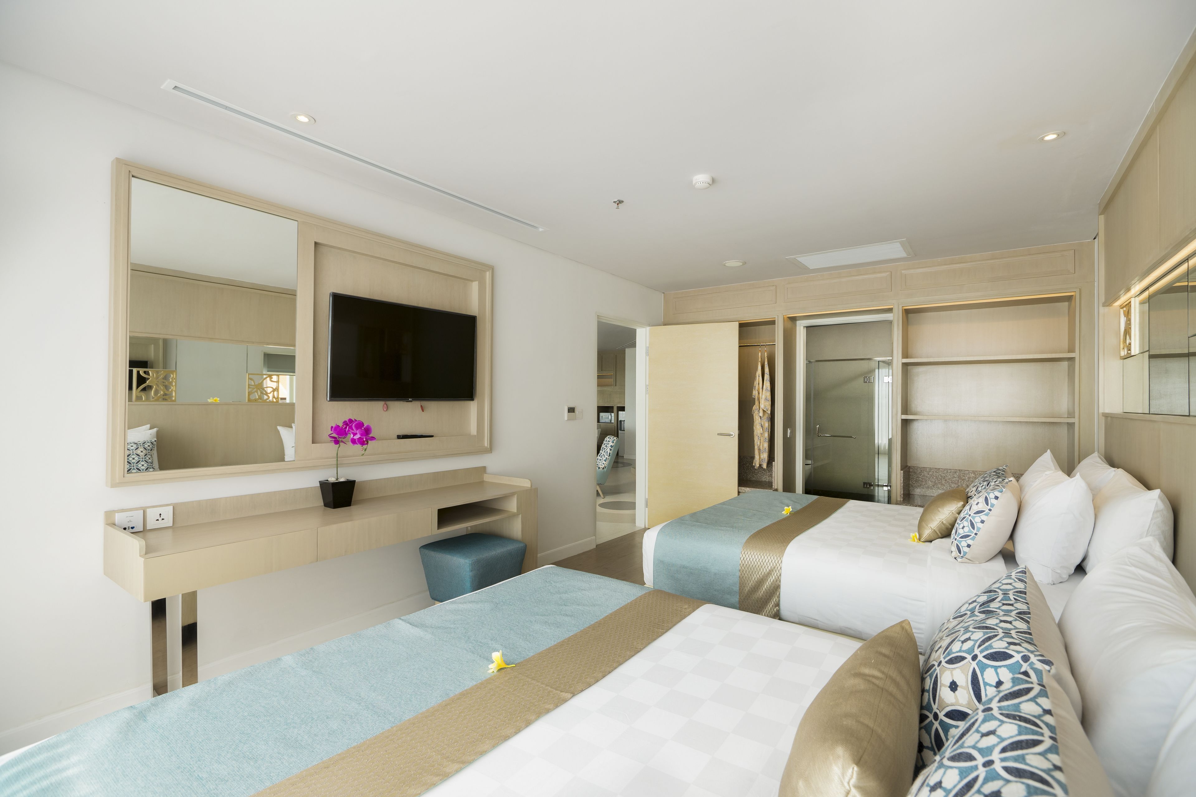 Een hotelkamer met twee bedden, een televisie, een spiegel en een badkamer met douche.