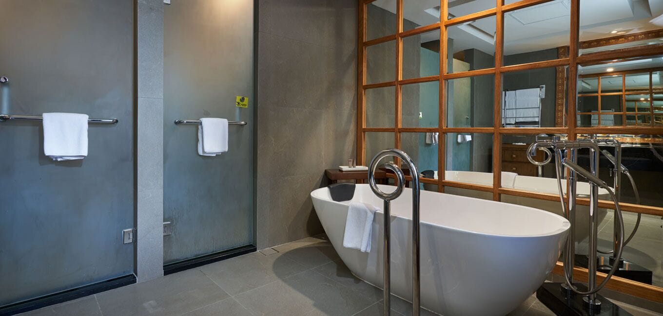 A modern bathroom with a freestanding bathtub, a glass shower enclosure, and a large mirror with a wooden frame.