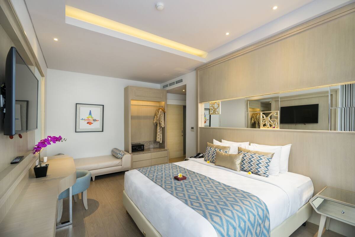 Une chambre d’hôtel moderne équipée d’un grand lit, d’un bureau, d’une chaise, d’une télévision et d’un espace douche.