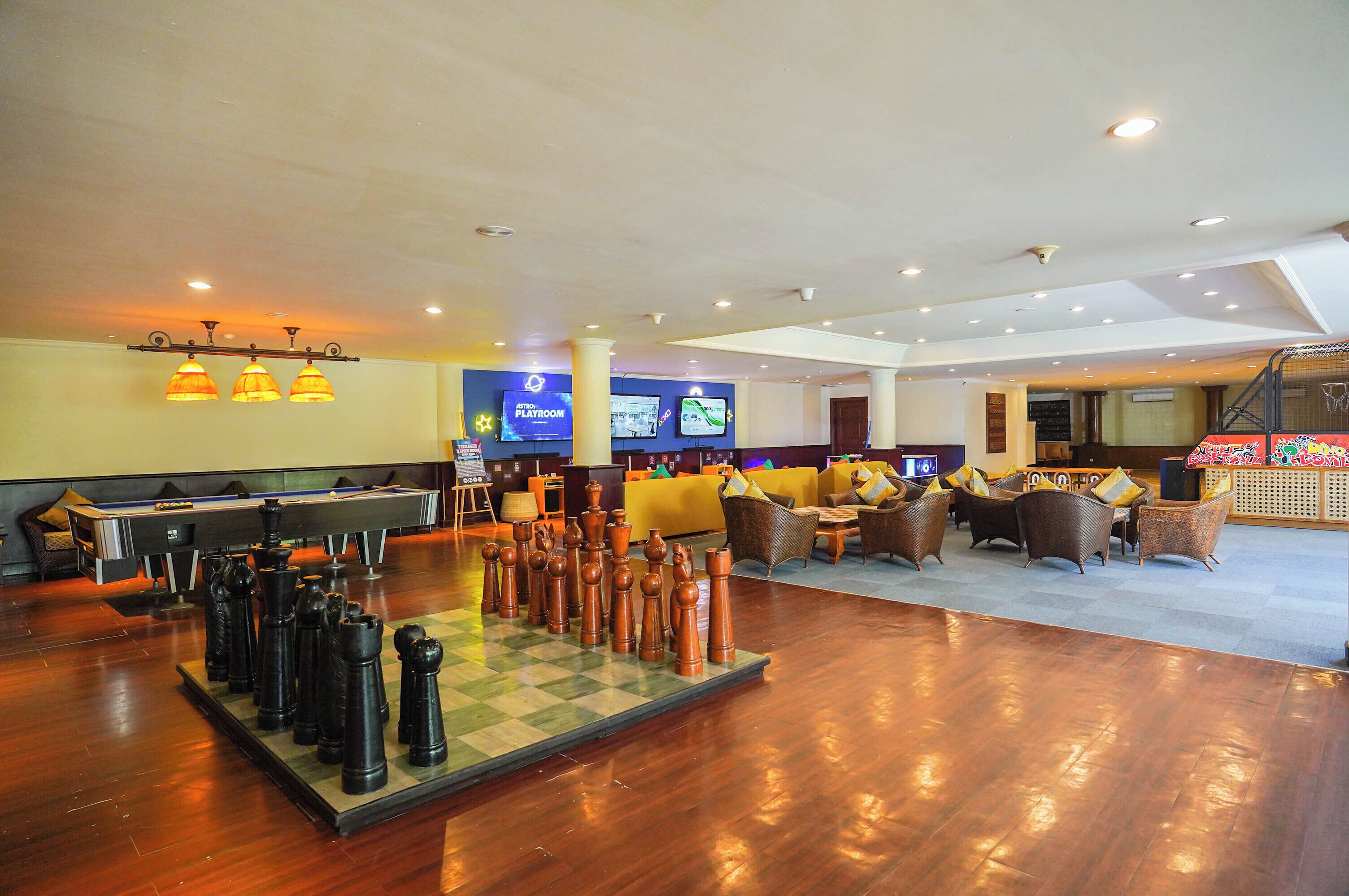 A spacious lobby with a large chess table, comfortable seating, and a billiards table.