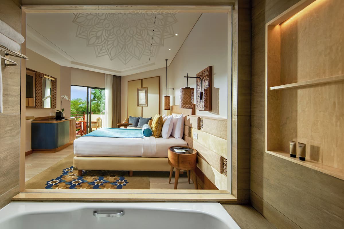 Une chambre d’hôtel moderne, dotée d’un grand lit, d’un bureau et offrant une vue sur l’extérieur.