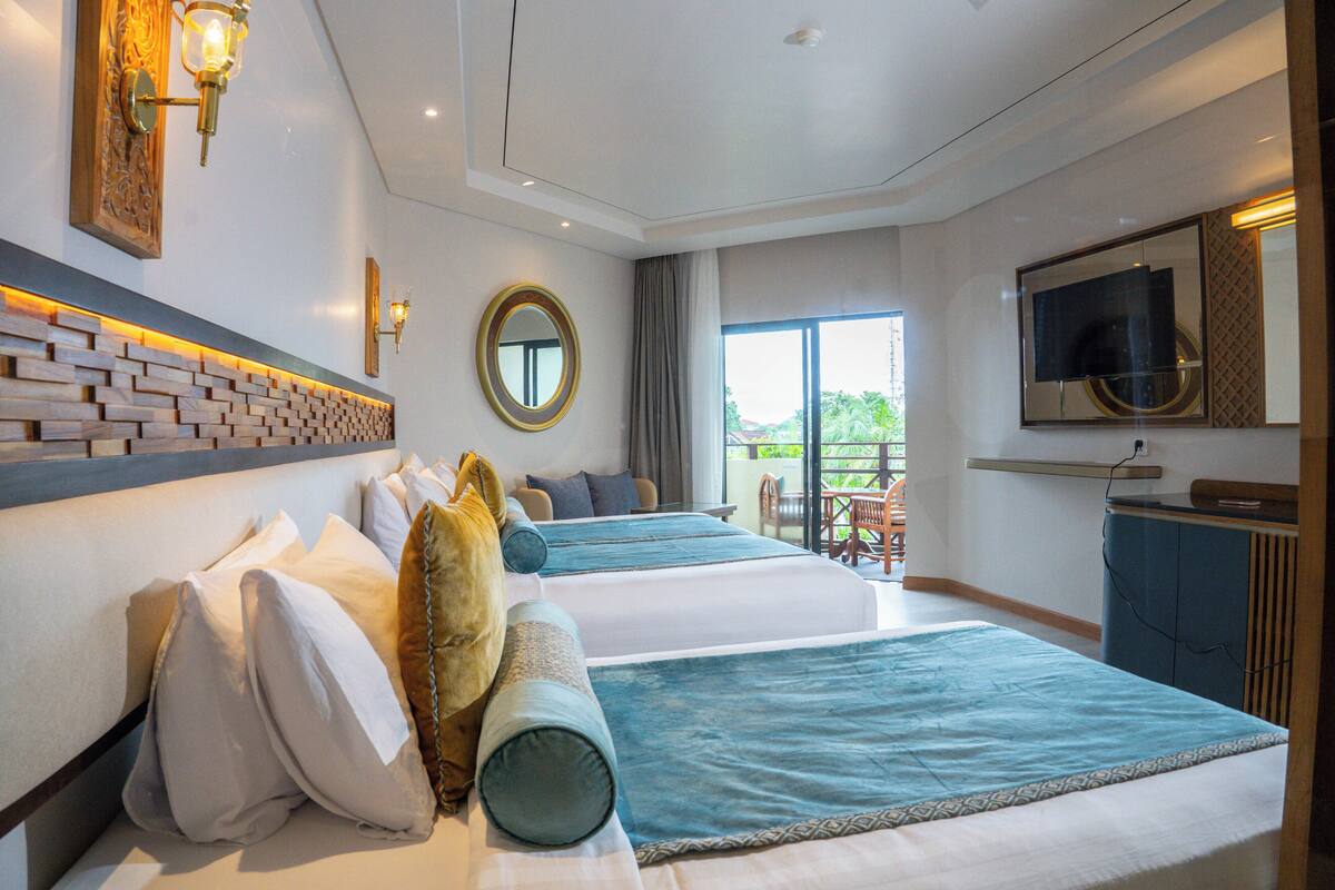 Une chambre d’hôtel avec deux lits, une télévision, un balcon et un mur décoratif en briques.