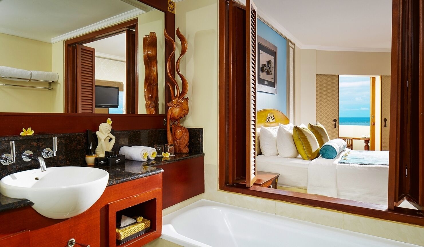 A bathroom with a large white sink, wooden vanity, and a bathtub.