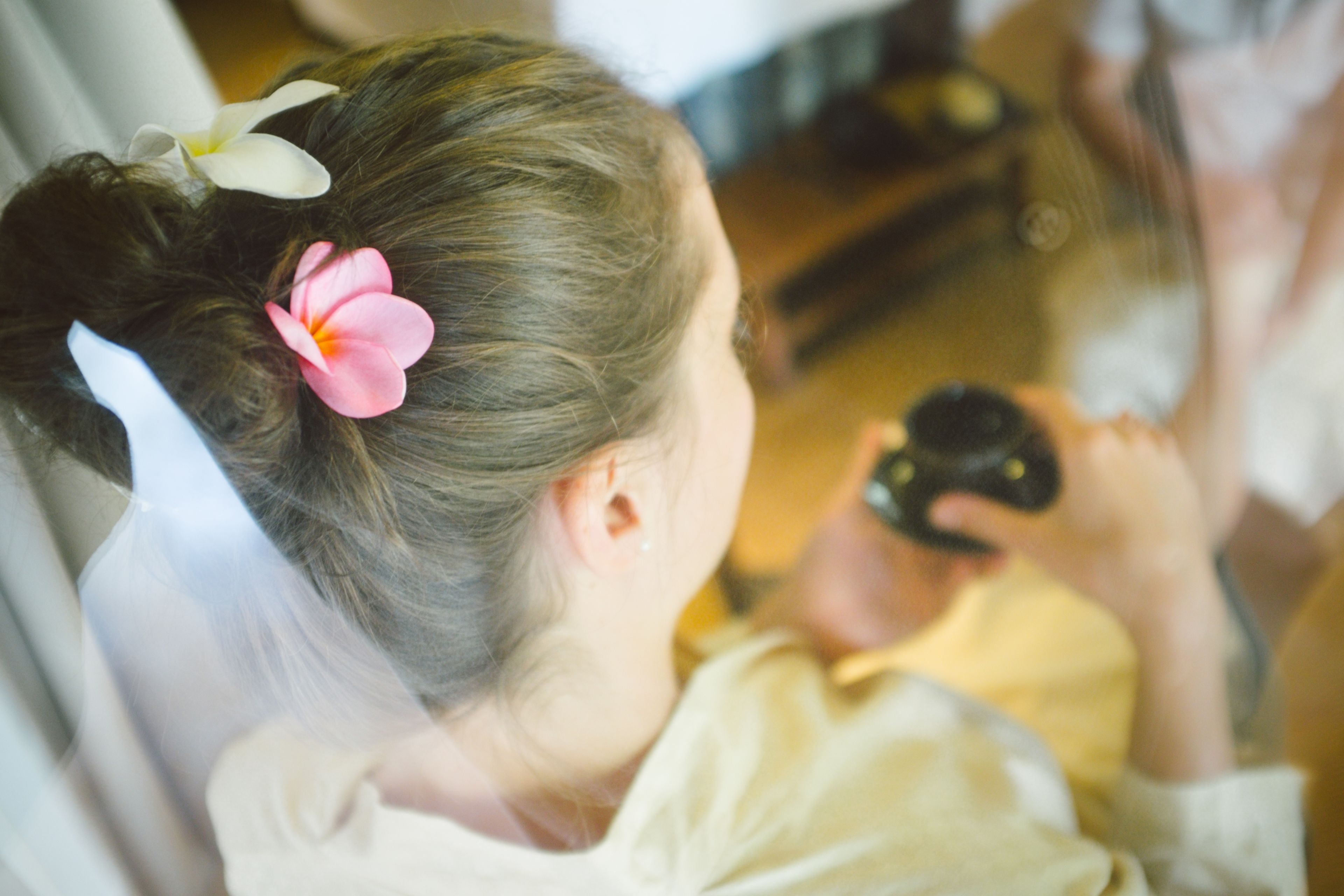 A person with a flower in their hair, a camera, and a reflection in a mirror.