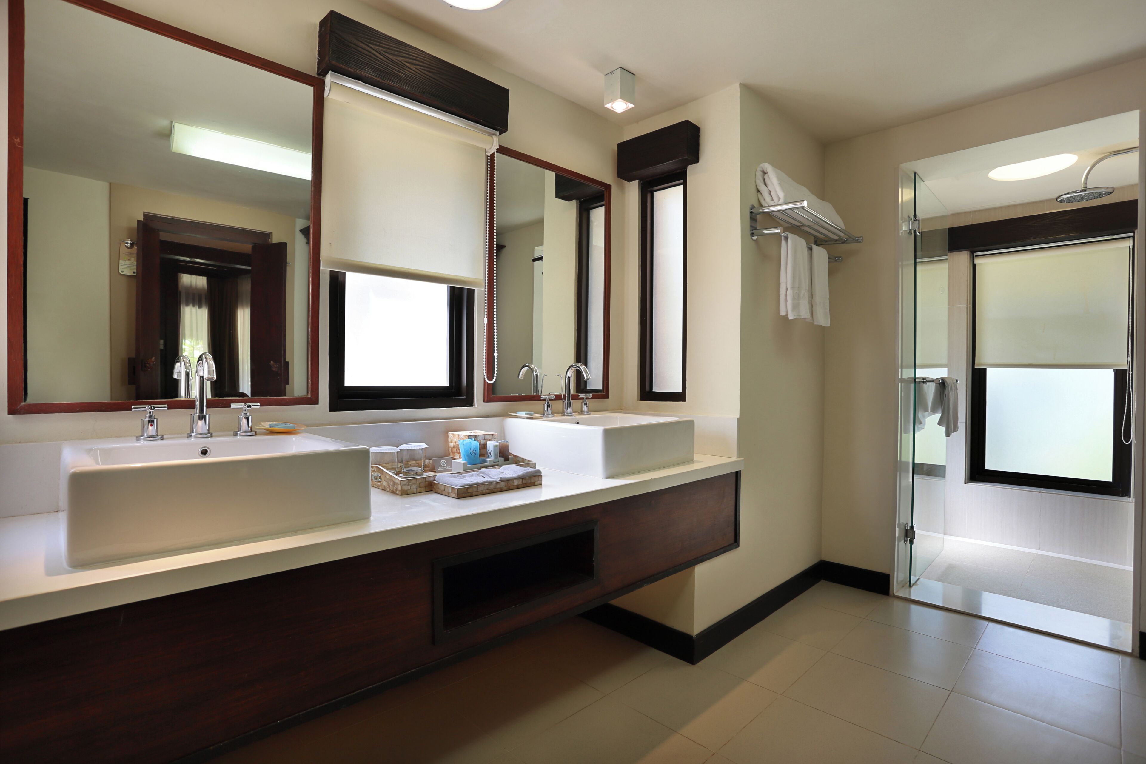 A modern bathroom with two sinks, a large mirror, and a glass shower enclosure.
