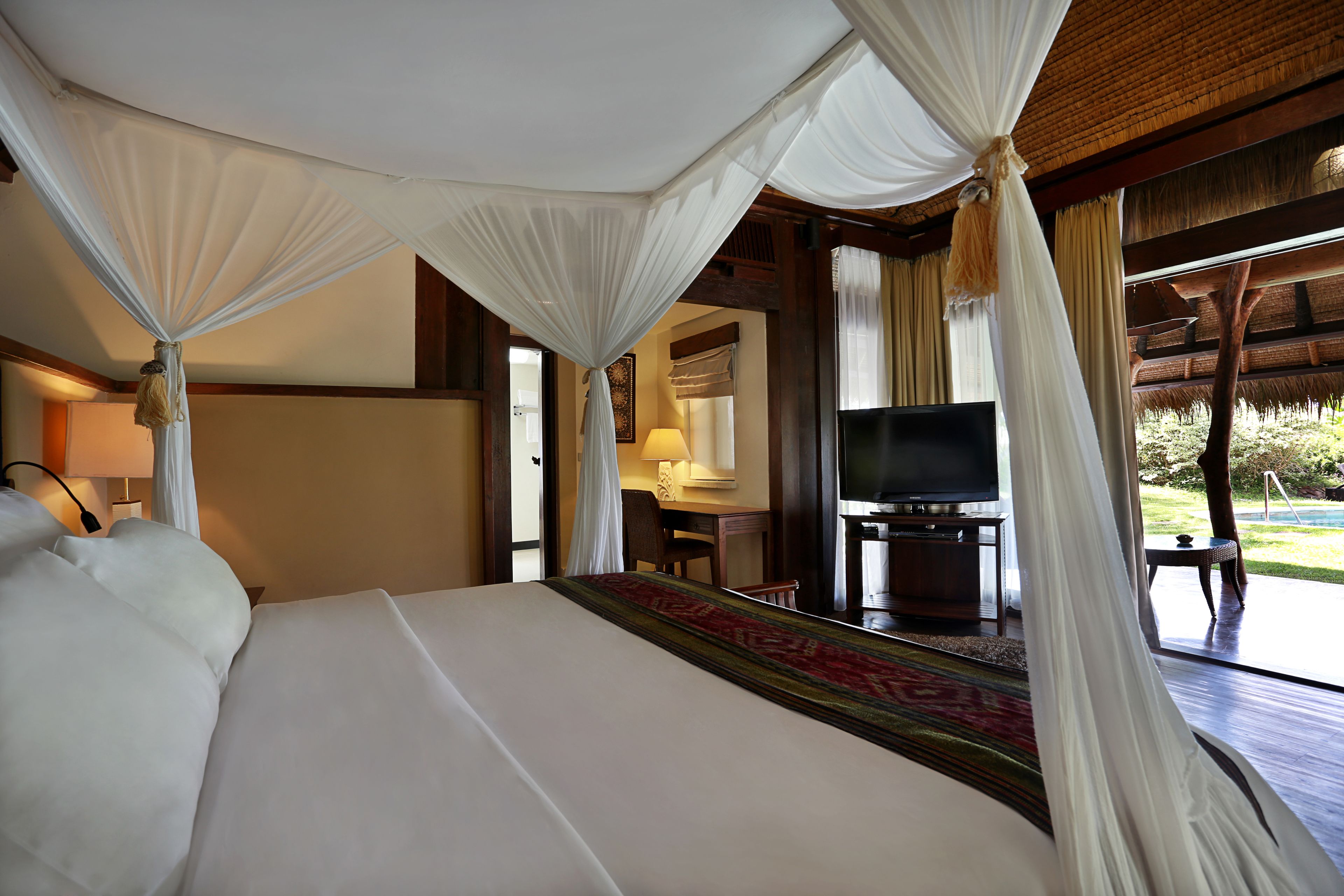 A hotel room with a bed, a desk, a television, and a view of the outdoors.