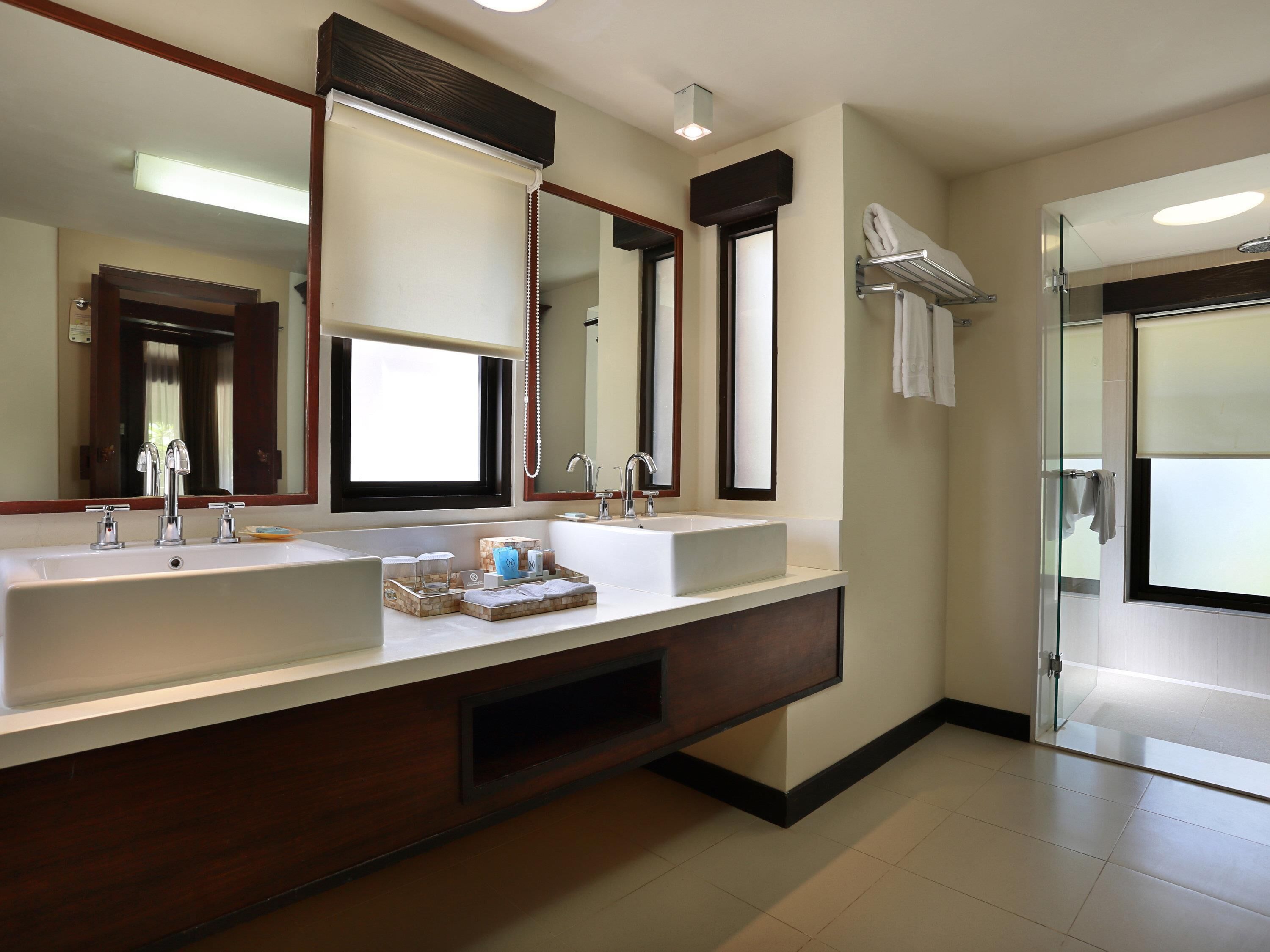 A modern bathroom with dual sinks, a large mirror, and a glass shower enclosure.