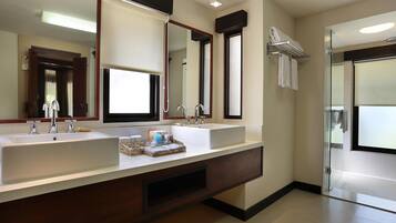 A modern bathroom with dual sinks, a large mirror, and a glass shower enclosure.