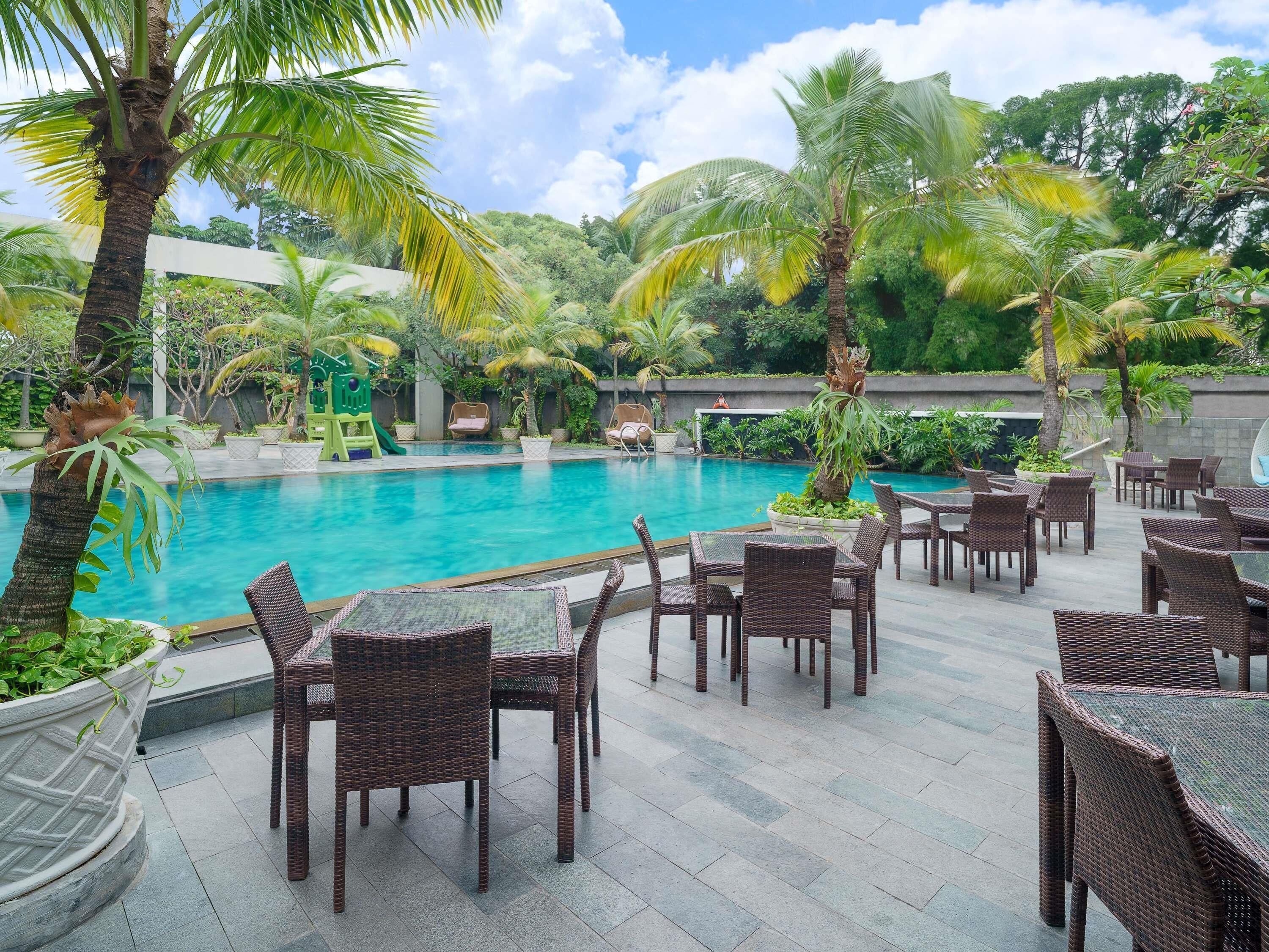 A poolside area with wicker furniture and palm trees.