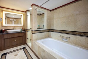 A bathroom with a bathtub, a sink, a mirror, and a shower area. - Novotel Solo (Surakarta)