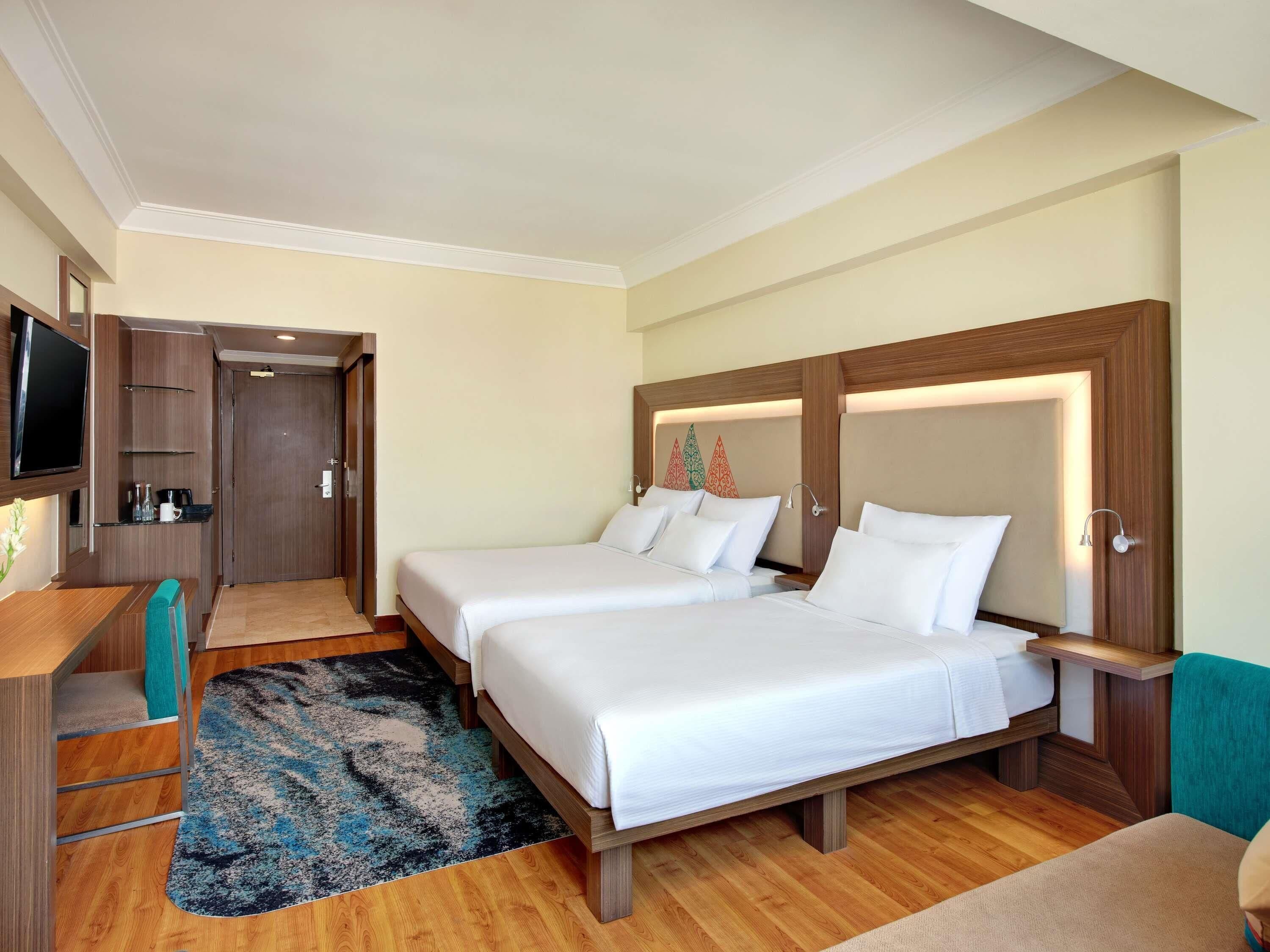 Une chambre d’hôtel avec deux lits, un bureau, une télévision et un espace douche.