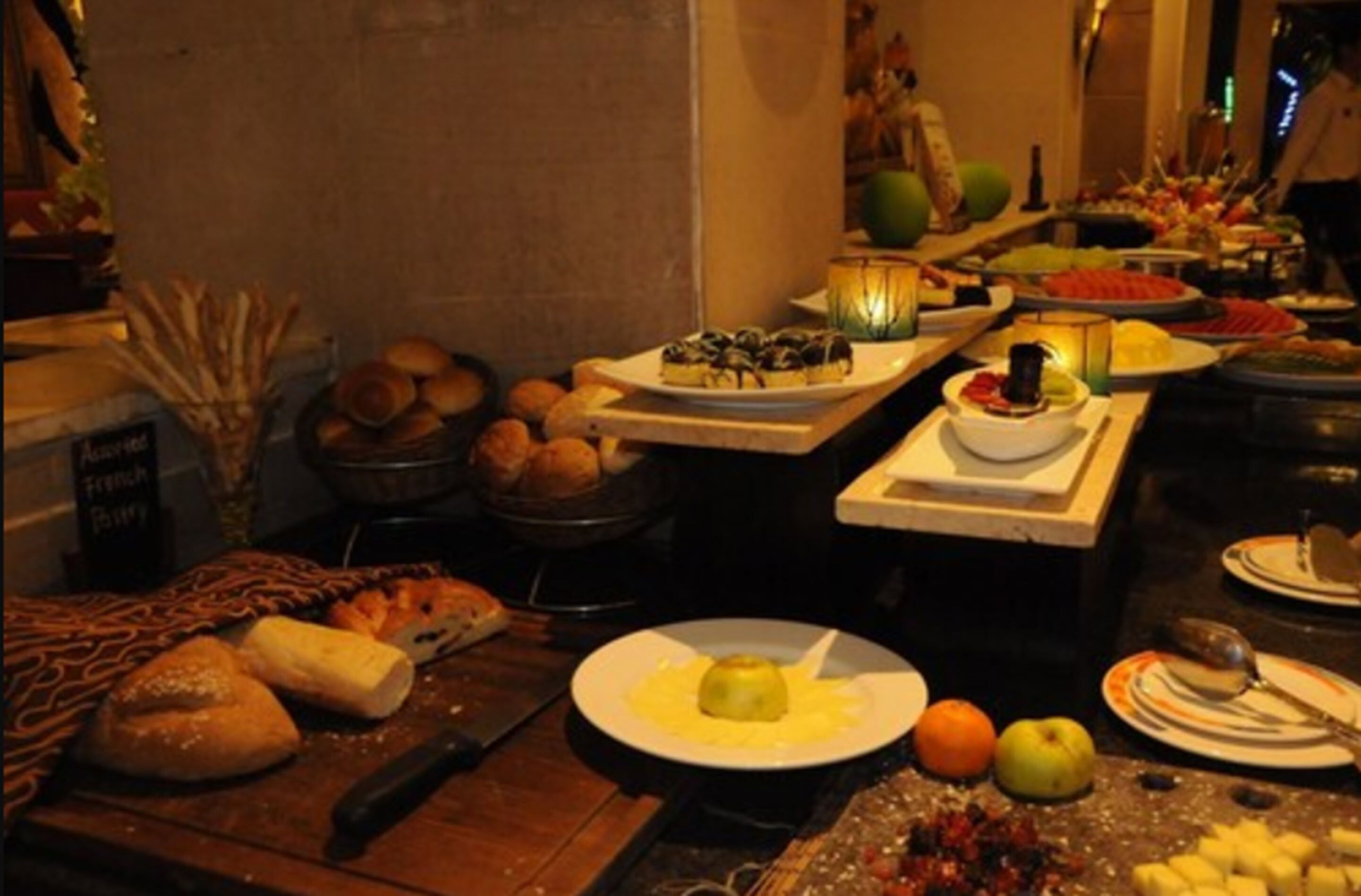 Una mesa de buffet con diversos platos, incluyendo pan, frutas y postres.