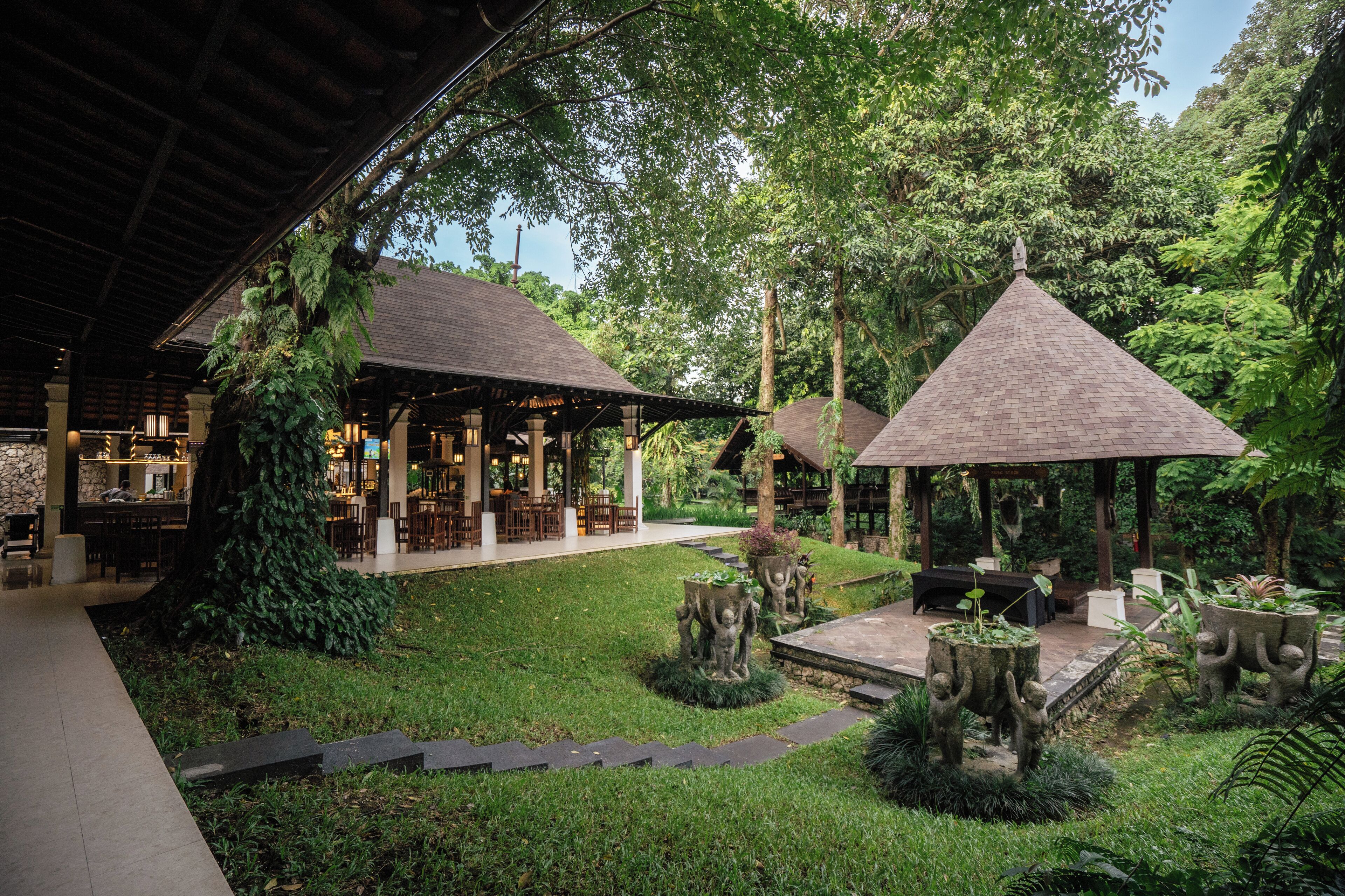 A courtyard with a covered seating area, stone sculptures, and lush greenery.