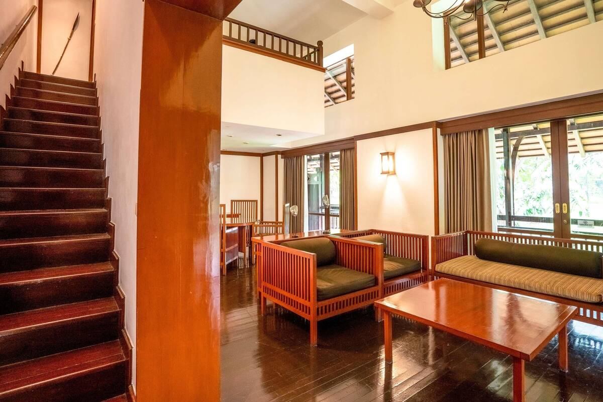 A staircase leading to a second-floor balcony with a view of greenery.