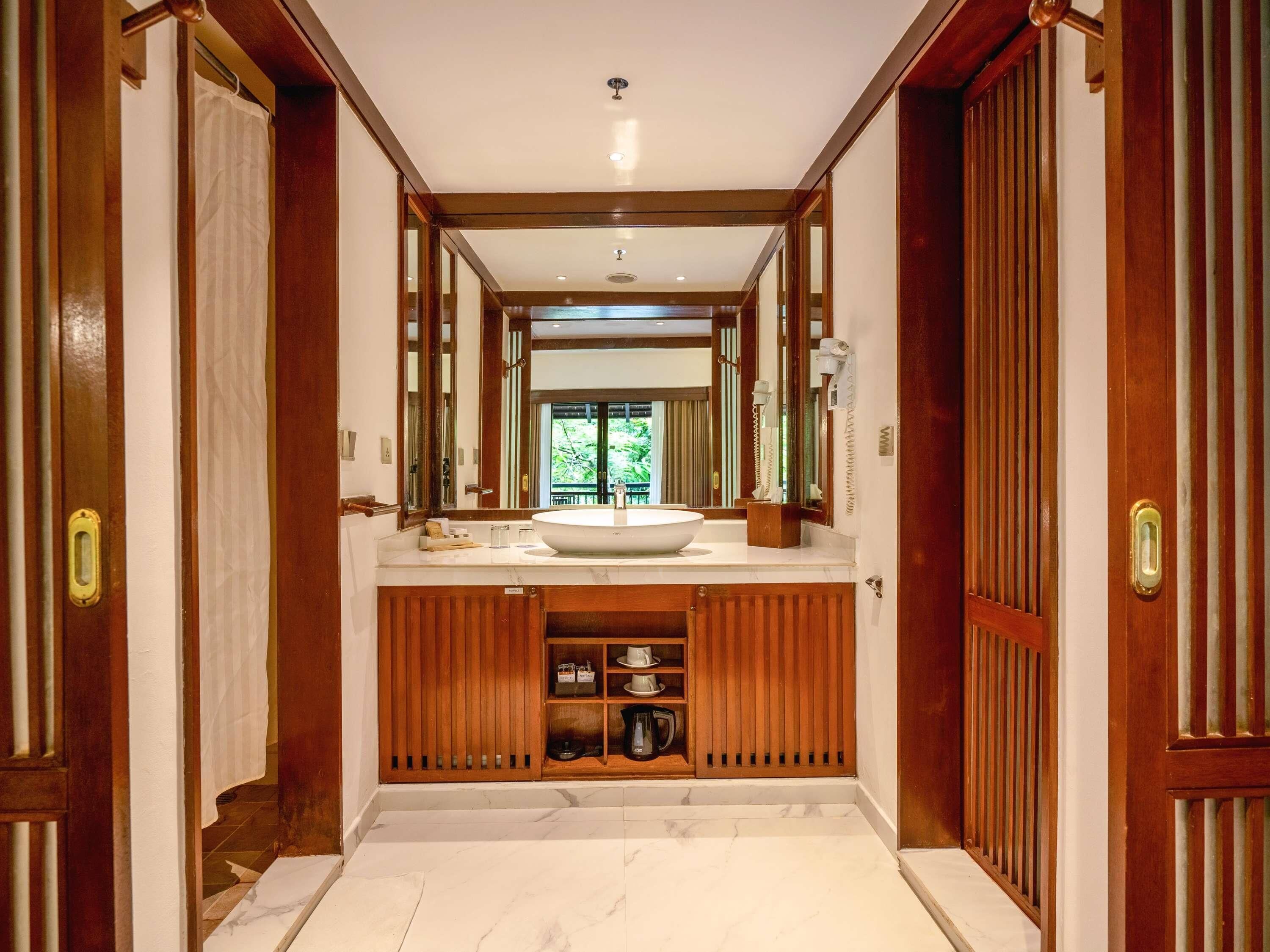 A spacious bathroom with a large sink, wooden vanity, and a large mirror.