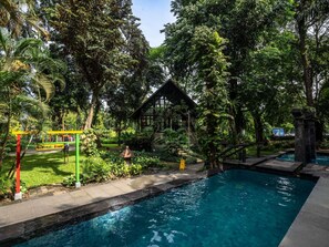 A pool surrounded by lush greenery and a wooden structure. - Novotel Bogor Golf Resort & Convention Center (Bogor)