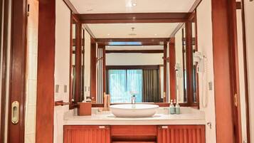 Une salle de bain d’hôtel avec un grand lavabo, un miroir et des meubles en bois.