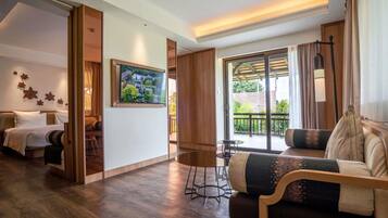 A hotel room with a bed, a sofa, a TV mounted on the wall, and a balcony with a view.