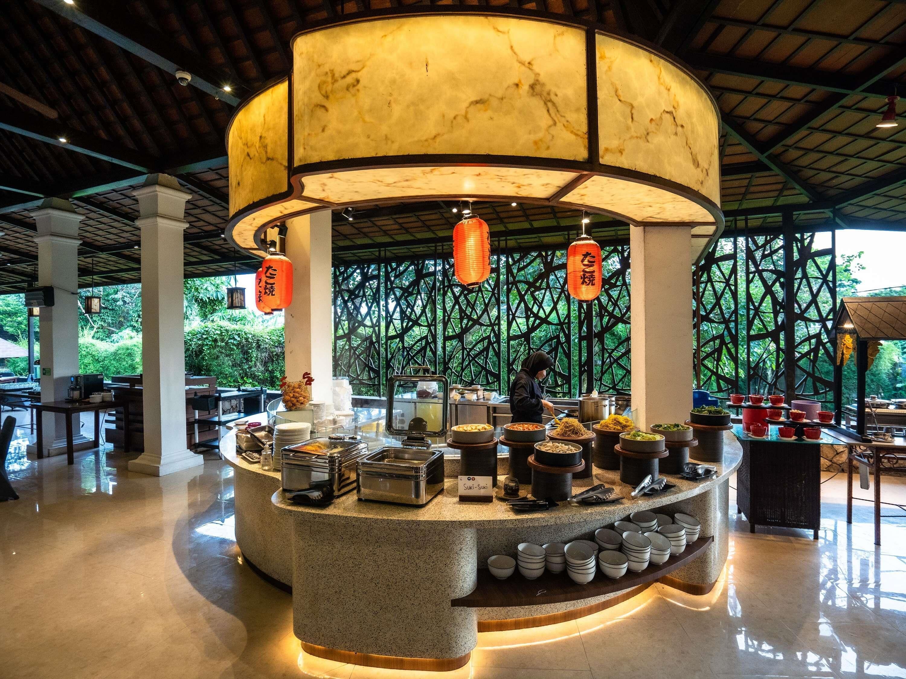 A restaurant with a central serving counter, multiple dishes, and a person preparing food.