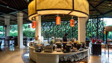 A restaurant with a central serving counter, multiple dishes, and a person preparing food.