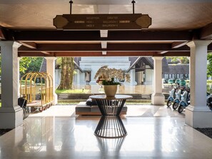 A reception area with directional signs, a potted plant, a seating area, and a scooter parking area. - Novotel Bogor Golf Resort & Convention Center (Bogor)
