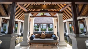 A covered outdoor seating area with a swing, columns, and a view of a building in the background. - Novotel Bogor Golf Resort & Convention Center (Bogor)