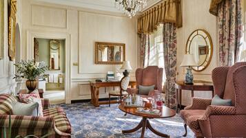 A spacious living room with a large chandelier, plush seating, and a decorative mirror.
