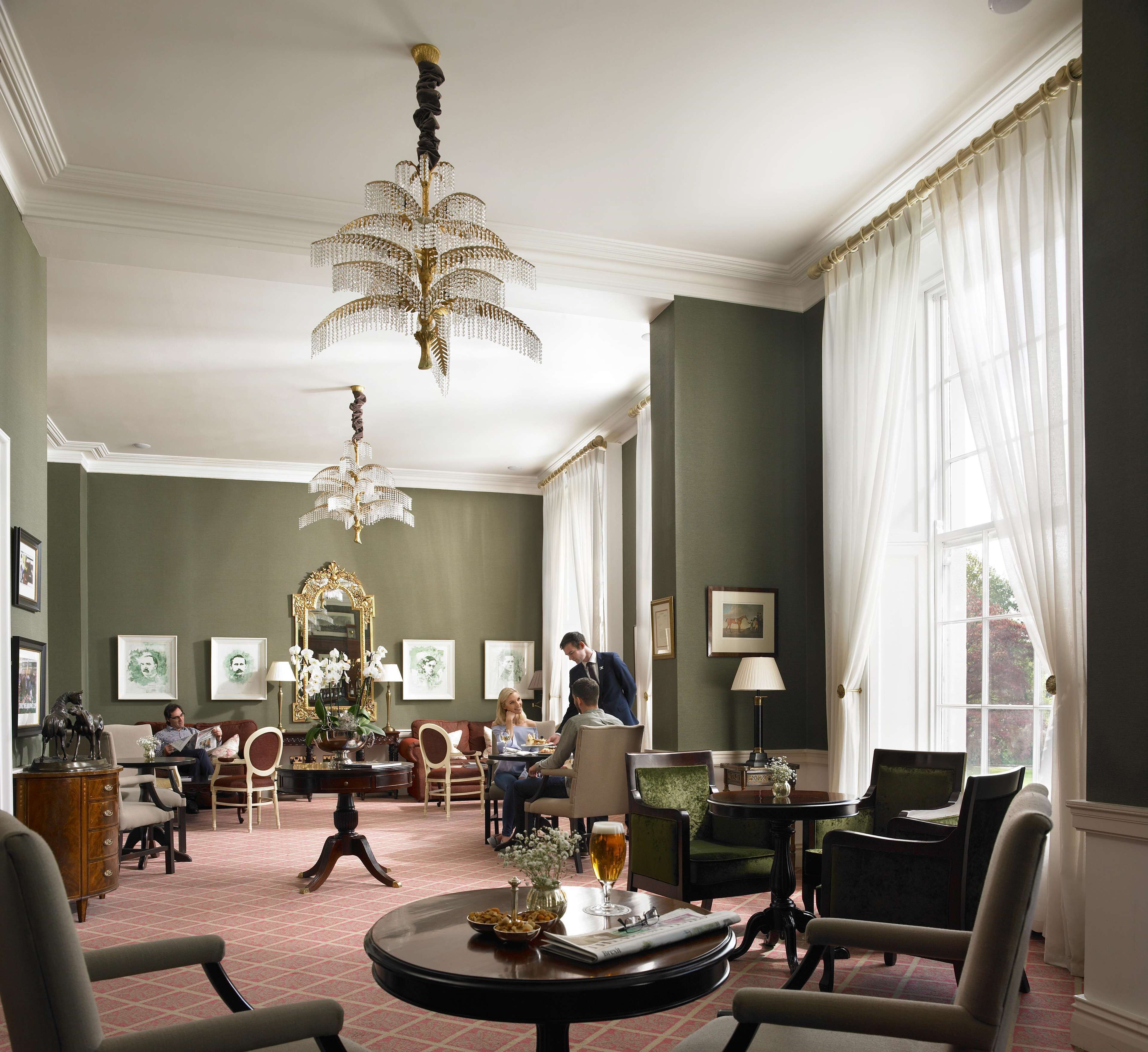 A spacious room with a large chandelier, comfortable seating, and artwork on the walls.