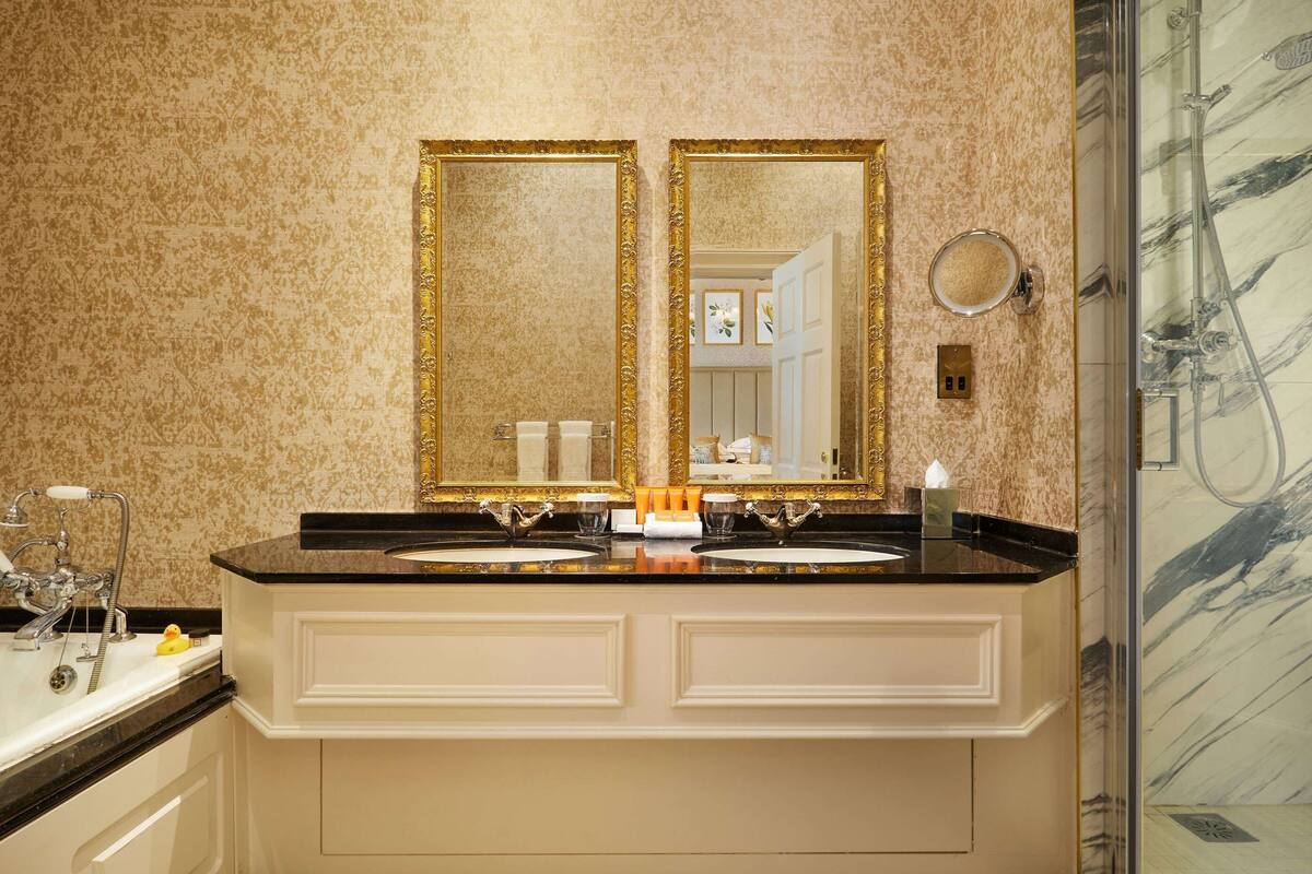 A bathroom with two sinks, a large mirror, and a marble wall.