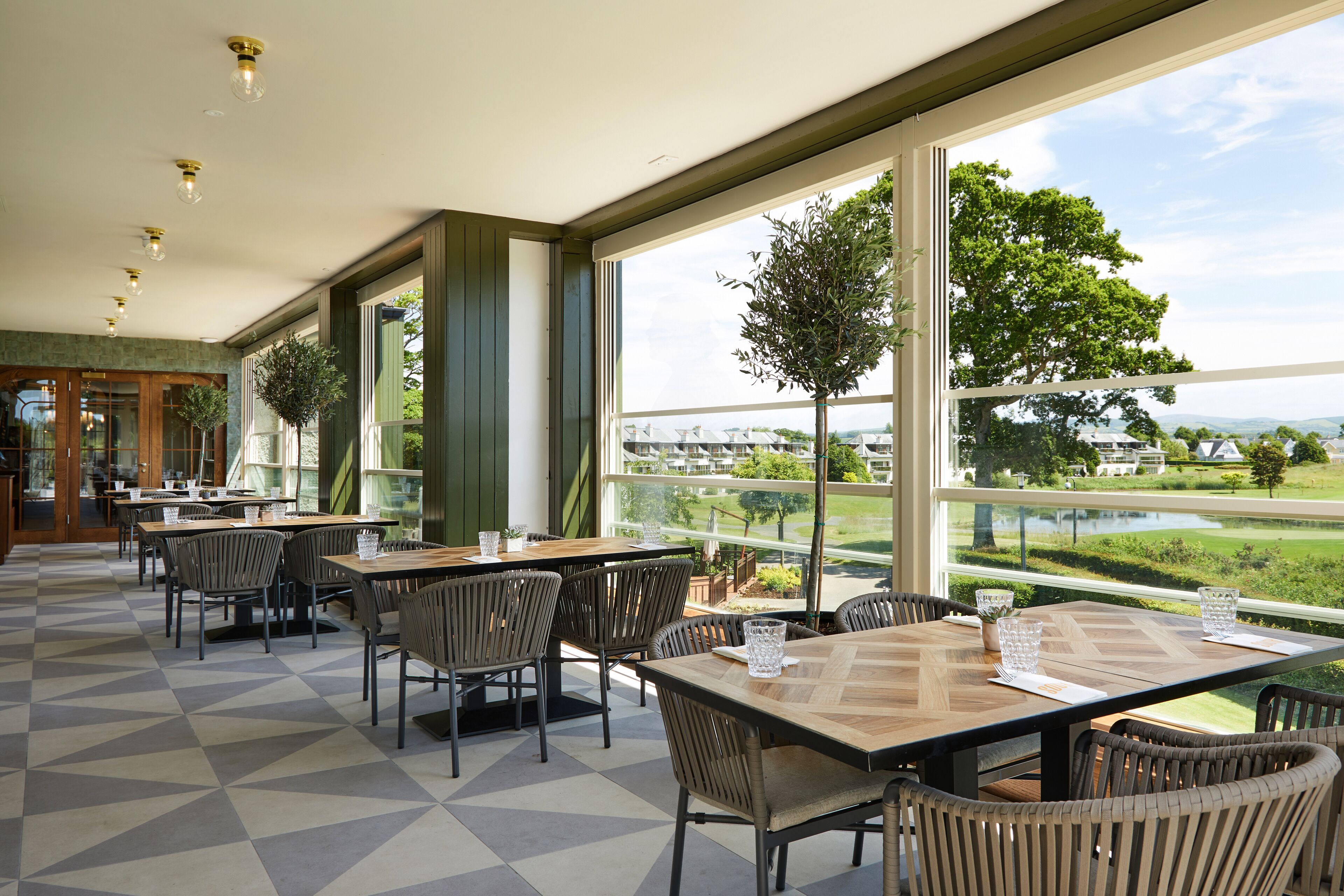 Un restaurante con amplios ventanales, mesas y sillas.