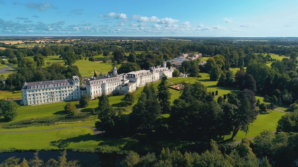 A large, historic building with a symmetrical facade, surrounded by expansive green lawns and a body of water. - The K Club (Straffan)